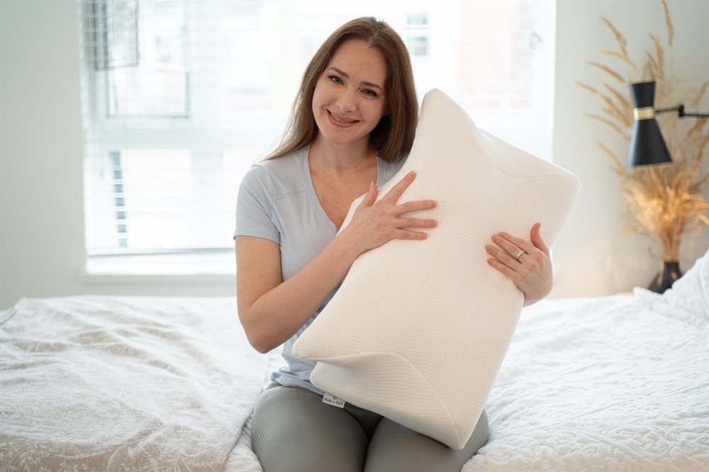 Maas and Bath Ergo Z ergonomic memory foam pillow held by a happy sleeper